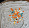 A heather gray short-sleeve t-shirt with a colorful graphic on the front featuring the text 'AXELSTRONG' and 'METACHROMATIC LEUKODYSTROPHY' along with various illustrative elements like a butterfly, stars, dice, and an 8-ball. 
